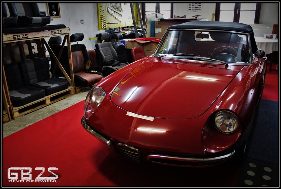 atelier de sellerie avec une Alfa Romeo Duetto Spider au centre